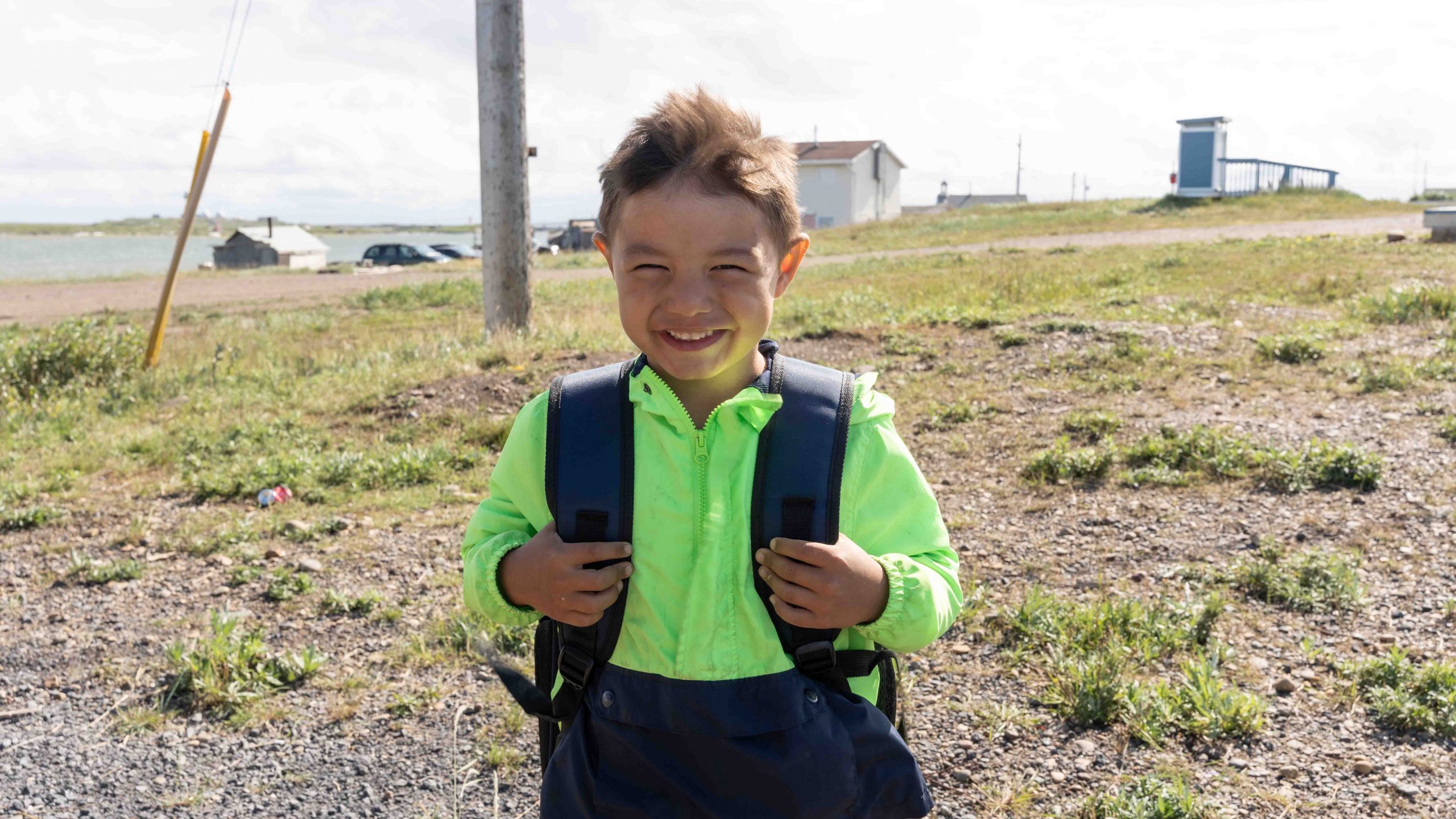 Native boy in the Arctic North of Canada smiles at the camera after receiving a backpack for school.